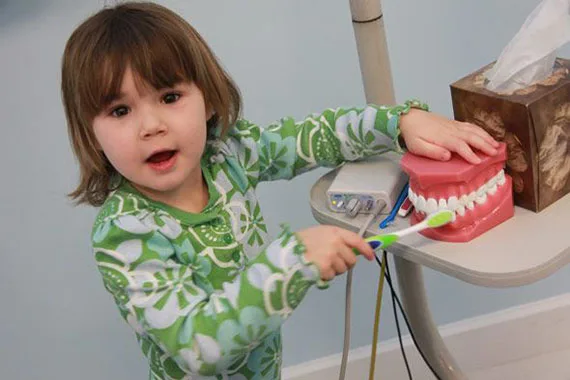 Young patient practicing brushing on a tooth model