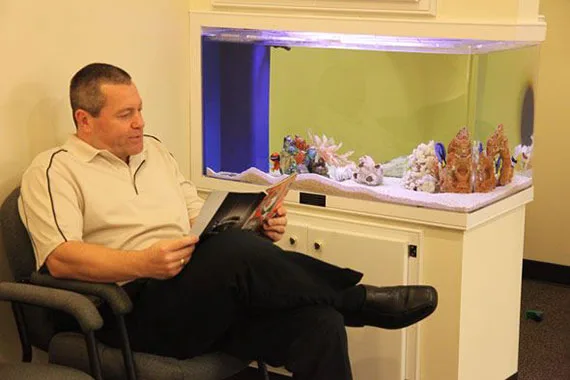 Patient relaxing in the waiting area by the aquarium